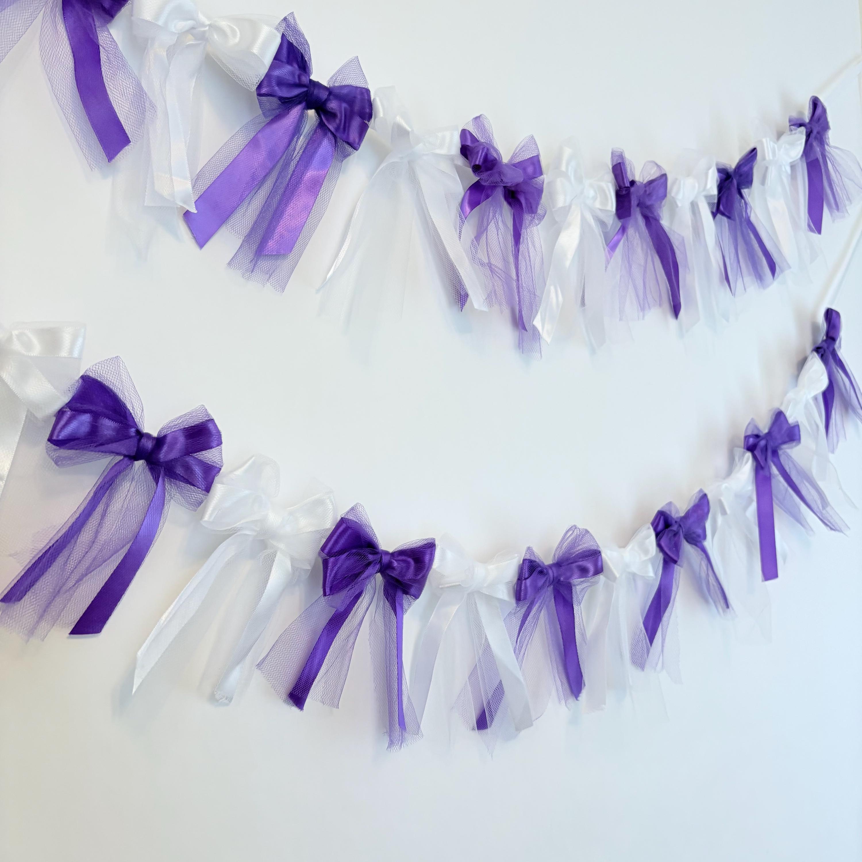 A white box with a purple ribbon around it and a bow on the top 