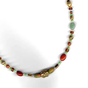 May include: A beaded necklace featuring a mix of red, green, and gold-toned beads, including small lime green spacers and textured metallic gold accents. The necklace includes a gold-tone chain extender with a small circular charm at the end.