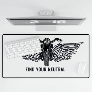 May include: White rectangular desk mat with a black motorcycle design and the text "FIND YOUR NEUTRAL". The motorcycle has wings. A white keyboard and mouse are on the mat. A computer monitor is above the mat.