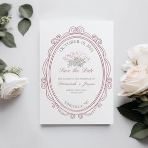 May include: A white wedding invitation featuring a mauve oval frame and floral details. The text reads "Save the Date", with the wedding date, names, and location. Decorative flowers are arranged around the invitation.
