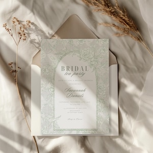 Può includere: Un invito per un tea party nuziale con un design floreale in morbidi toni verdi e grigi. L'invito include il testo "BRIDAL tea party" e i dettagli per un addio al nubilato in onore di Savannah Daniels. L'invito è all'interno di una busta color crema.