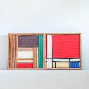Könnte beinhalten: Zwei quadratische Holzrahmen mit Wandkunst aus fest gewickeltem, farbigem Garn. Das linke Stück zeigt braune, beige, weiße, rote und grüne vertikale und horizontale Blöcke. Das rechte Stück zeigt rote, weiße, blaue und beige Abschnitte.