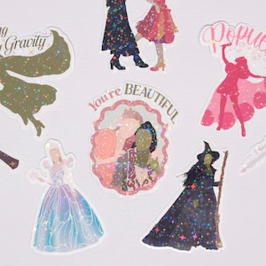 May include: A collection of colorful stickers featuring illustrations of fairytale characters and the text "You're Beautiful". The stickers have a glittery, holographic effect, with various shades of pink, blue, green, and black. The stickers are in various shapes and sizes.