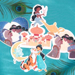 Puede incluir: Una colección de pegatinas coloridas con personajes y escenas de la película de animación Aladdin. Las pegatinas incluyen imágenes de la princesa Jasmine, la lámpara del Genio y un tigre. Las pegatinas tienen un efecto brillante.