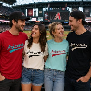 May include: Four short-sleeved t-shirts featuring the word Arizona in a cursive script font with a swoosh underline. The shirts are red, white, light blue, and black. Two individuals wear black baseball caps with a red and white logo.