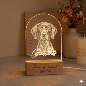 May include: A lighted dog portrait lamp with the name "Charlie" and a paw print. The base is wood and has the text "Forever Loved 2019-2026". The lamp features a detailed illustration of a dog.