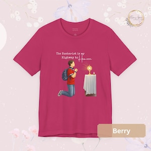 Unisex Bella and Canvas Catholic t-shirt featuring Saint Carlo Acutis kneeling in Eucharistic Adoration with the quote “The Eucharist is my Highway to Heaven,” Christian faith apparel for men and women. Perfect for Catholic gifts.