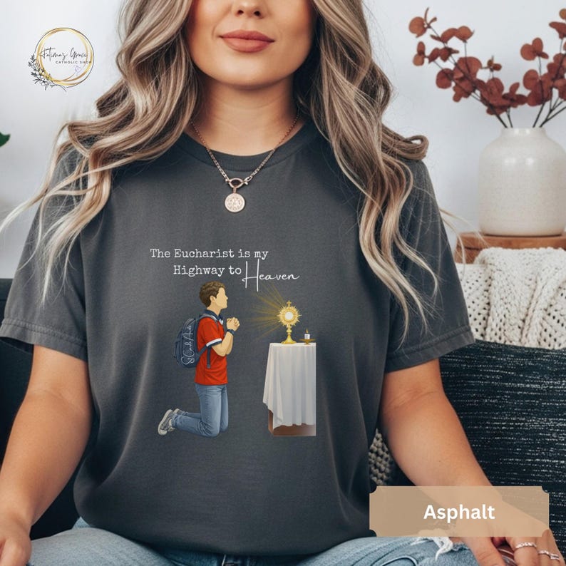Unisex Bella and Canvas Catholic t-shirt featuring Saint Carlo Acutis kneeling in Eucharistic Adoration with the quote “The Eucharist is my Highway to Heaven,” Christian faith apparel for men and women. Perfect for Catholic gifts.