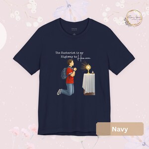 Unisex Bella and Canvas Catholic t-shirt featuring Saint Carlo Acutis kneeling in Eucharistic Adoration with the quote “The Eucharist is my Highway to Heaven,” Christian faith apparel for men and women. Perfect for Catholic gifts.