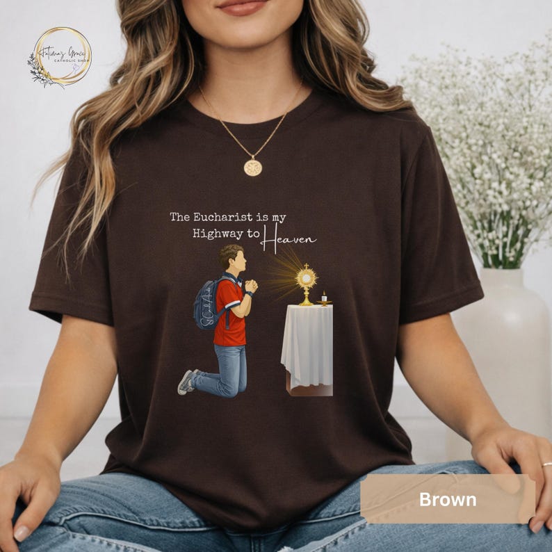 Unisex Bella and Canvas Catholic t-shirt featuring Saint Carlo Acutis kneeling in Eucharistic Adoration with the quote “The Eucharist is my Highway to Heaven,” Christian faith apparel for men and women. Perfect for Catholic gifts.