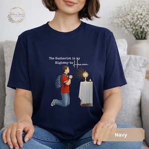 Unisex Bella and Canvas Catholic t-shirt featuring Saint Carlo Acutis kneeling in Eucharistic Adoration with the quote “The Eucharist is my Highway to Heaven,” Christian faith apparel for men and women. Perfect for Catholic gifts.
