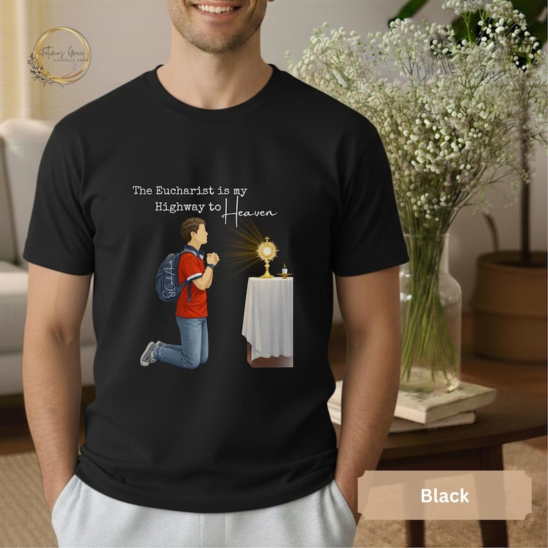Unisex Bella and Canvas Catholic t-shirt featuring Saint Carlo Acutis kneeling in Eucharistic Adoration with the quote “The Eucharist is my Highway to Heaven,” Christian faith apparel for men and women. Perfect for Catholic gifts.