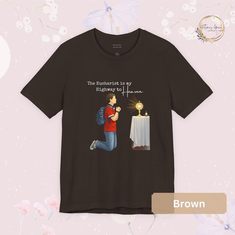 Unisex Bella and Canvas Catholic t-shirt featuring Saint Carlo Acutis kneeling in Eucharistic Adoration with the quote “The Eucharist is my Highway to Heaven,” Christian faith apparel for men and women. Perfect for Catholic gifts.