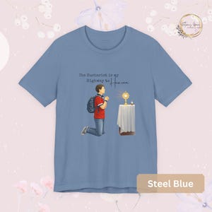 Unisex Bella and Canvas Catholic t-shirt featuring Saint Carlo Acutis kneeling in Eucharistic Adoration with the quote “The Eucharist is my Highway to Heaven,” Christian faith apparel for men and women. Perfect for Catholic gifts.
