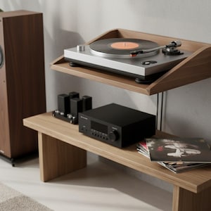K&ouml;nnte beinhalten: Holz-Audioanlage mit Plattenspieler und Schallplatte, einem schwarzen Verst&auml;rker und einem hohen Lautsprecher. Das Setup befindet sich auf einem Holzregal und einer Bank und schafft eine minimalistische &Auml;sthetik.
