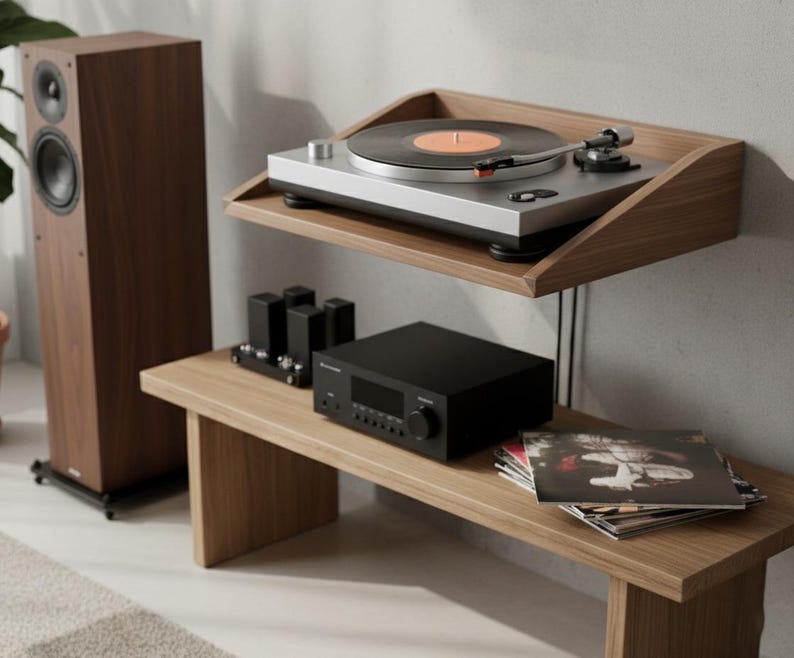 K&ouml;nnte beinhalten: Holz-Audioanlage mit Plattenspieler und Schallplatte, einem schwarzen Verst&auml;rker und einem hohen Lautsprecher. Das Setup befindet sich auf einem Holzregal und einer Bank und schafft eine minimalistische &Auml;sthetik.