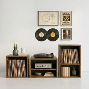 Può includere: Un'installazione di intrattenimento domestico con scaffali in legno, un giradischi e opere d'arte incorniciate. L'installazione comprende un giradischi, un amplificatore e dischi in vinile. Sono presenti elementi decorativi.