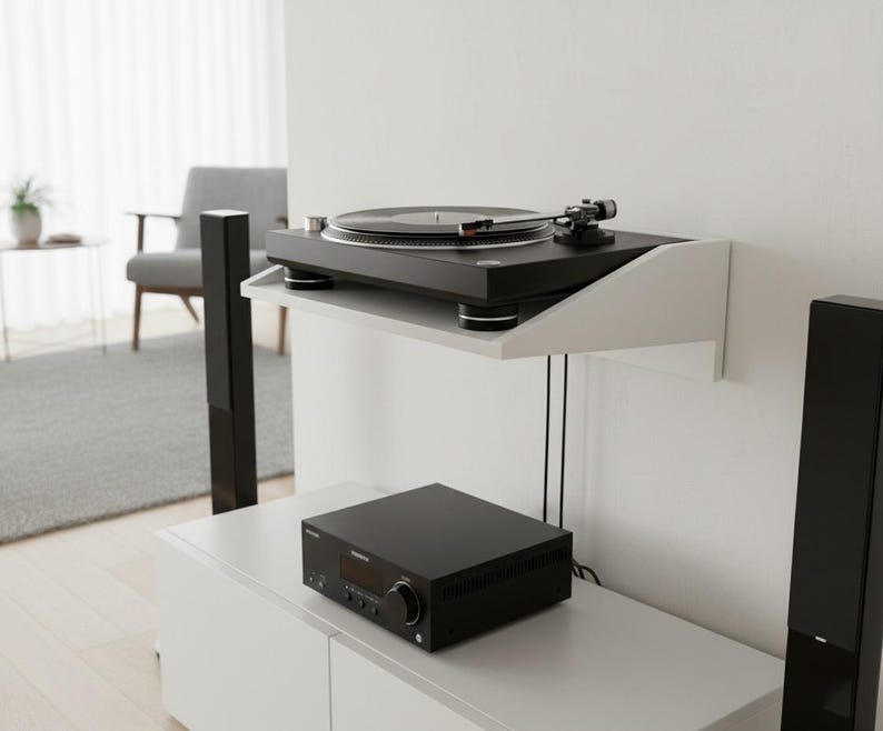 K&ouml;nnte beinhalten: Ein schwarzer Plattenspieler steht auf einem wei&szlig;en, an der Wand befestigten Regal. Darunter befindet sich ein schwarzer Stereo-Receiver auf einem wei&szlig;en Schrank. Hohe schwarze Lautsprecher flankieren das Setup und bilden ein modernes Audiosystem.