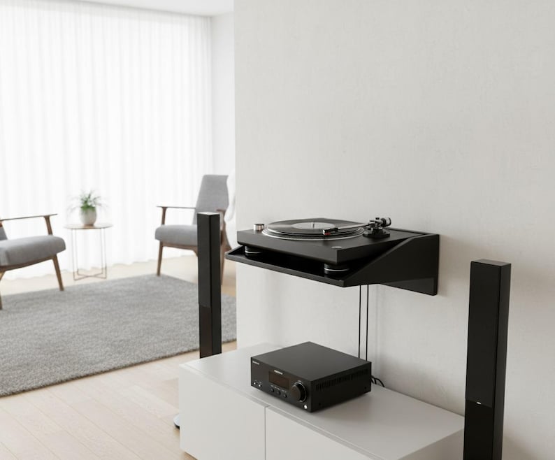 K&ouml;nnte beinhalten: Ein schwarzer Plattenspieler auf einem schwarzen Wandregal, darunter ein schwarzer Receiver. Zwei schwarze Lautsprecher flankieren einen wei&szlig;en Schrank. Der Raum hat ein minimalistisches Design mit grauen St&uuml;hlen und einem Teppich.