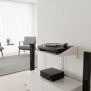 K&ouml;nnte beinhalten: Eine moderne Unterhaltungseinrichtung mit einem schwarzen Plattenspieler auf einem wei&szlig;en Regal. Darunter befindet sich ein schwarzer Receiver auf einem wei&szlig;en Schrank, flankiert von hohen schwarzen Lautsprechern. Der Raum hat ein minimalistisches Design mit neutralen Farben und nat&uuml;rlichem Licht.