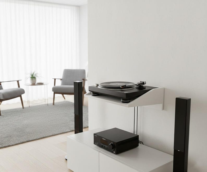 K&ouml;nnte beinhalten: Eine moderne Unterhaltungseinrichtung mit einem schwarzen Plattenspieler auf einem wei&szlig;en Regal. Darunter befindet sich ein schwarzer Receiver auf einem wei&szlig;en Schrank, flankiert von hohen schwarzen Lautsprechern. Der Raum hat ein minimalistisches Design mit neutralen Farben und nat&uuml;rlichem Licht.