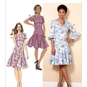 May include: Butterick sewing pattern B6514 featuring three dress designs. The dresses are illustrated with floral prints in pink, white, and blue. The pattern includes a variety of sleeve and neckline styles, suitable for creating custom dresses.