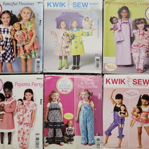 May include: Six sewing pattern envelopes from Ellie Mae Designs and Kwik Sew, each featuring photographs of children and dolls wearing matching outfits. The patterns include Fanciful Flounces, K3941, Coordinating Comfy Loungewear, Pajama Party, Ruffled & Ready Play Clothes, and K4054.