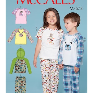 May include: McCall's M7678 pattern for children's pajamas. The image shows a variety of pajama designs, including a pink top with floral sleeves, a yellow top with a bear face, and a green hooded top with dinosaur print sleeves. The pajama sets are modeled by two children.