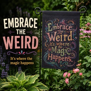 May include: A black garden flag with the words "Embrace the Weird. It's where the Magic Happens" in colorful, whimsical lettering. The flag is displayed in a garden setting with lush greenery and flowers.