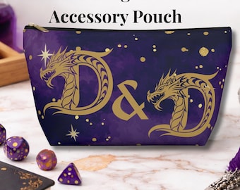 Op de afbeelding: Een paarse accessoiretas met een gouden draak en de letters "D&D". De tas heeft een zwarte ritssluiting en de tekst "Golden Dragon D&D Accessory Pouch" bovenaan. De achtergrond heeft een aquareleffect met gouden accenten.