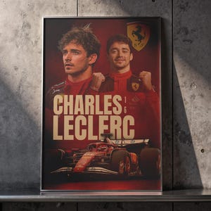 May include: A framed poster featuring Charles Leclerc, a Formula 1 driver, in a red and black racing suit. The poster includes the Ferrari logo and a red race car at the bottom. The name "CHARLES LECLERC" is prominently displayed in large, bold letters.