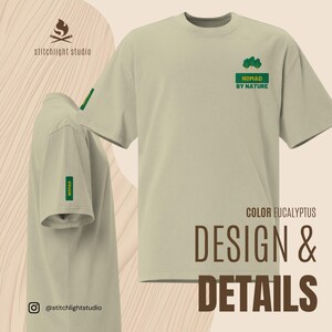 May include: A light green t-shirt with the text "NOMAD BY NATURE" and a tree graphic in green. The shirt also has the word "NOMAD" on the sleeve. The shirt is labeled "COLOR EUCALYPTUS" with "DESIGN & DETAILS" text.