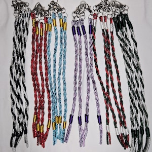 Peut inclure: Une collection de longes tressées colorées avec des mousquetons en métal. Les longes sont de différentes couleurs, dont noir et argent, rouge et or, bleu, violet et vert et argent. Chaque longe est en cordon torsadé.