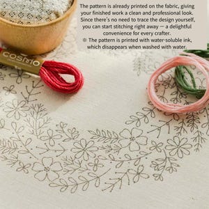 May include: Close-up of a fabric with a floral embroidery design. A red embroidery floss spool and a wooden bowl are visible. The text on the image says the pattern is printed with water-soluble ink.