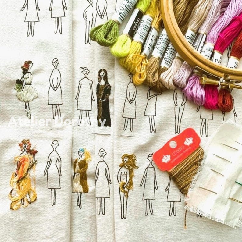 May include: A close-up of a fabric with embroidered figures and embroidery supplies. The fabric features embroidered figures in various outfits. Embroidery floss in shades of green, yellow, pink, and brown is arranged near an embroidery hoop and a spool of thread.
