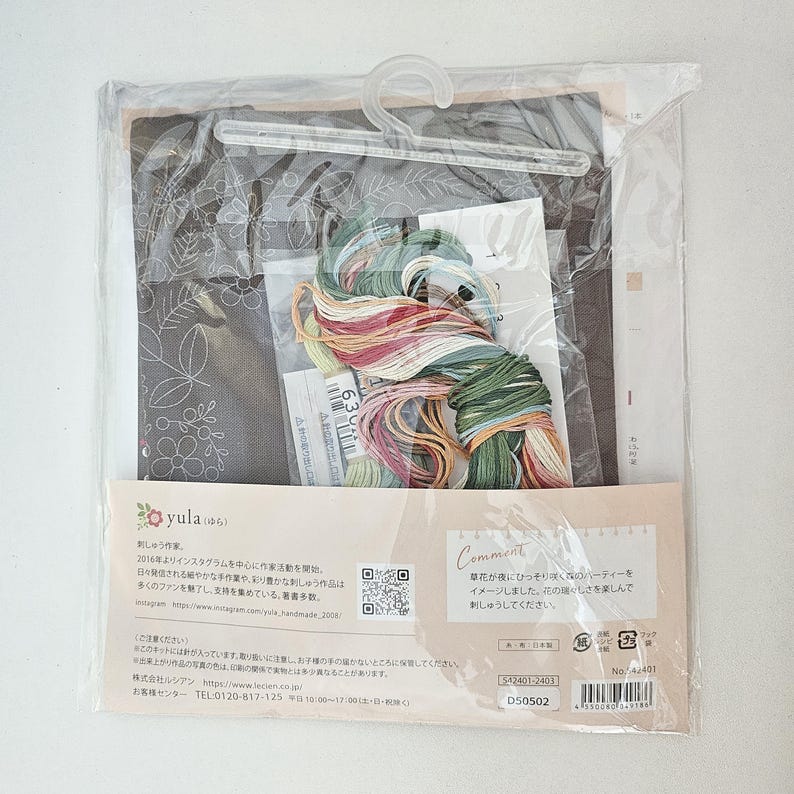 May include: A cross-stitch kit in a clear plastic bag. The kit includes a fabric with a floral design, embroidery floss in various colors, and instructions. The packaging features Japanese text and a QR code.