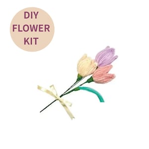 Può includere: Un kit di fiori fai-da-te con un bouquet di tre tulipani fatti a mano. I tulipani sono in colori pastello: crema, lavanda e pesca. Gli steli sono verdi, legati con un nastro color crema. Il kit include il testo "DIY FLOWER KIT".