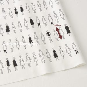 May include: White fabric with a repeating pattern of stylized figures in black. The figures are dressed in various outfits. A red arrow indicates a measurement of 2.1 inches.