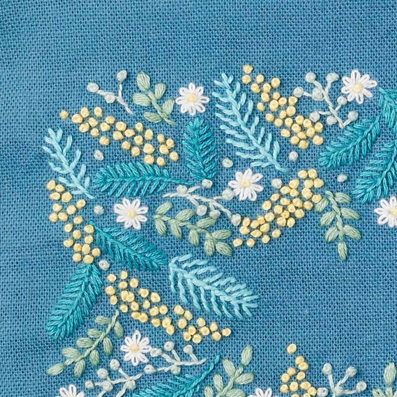 May include: Close-up of a teal fabric with embroidered floral design. The embroidery features yellow, white, and green flowers and leaves. The stitches are detailed and create a textured surface, showcasing the craft of hand embroidery.