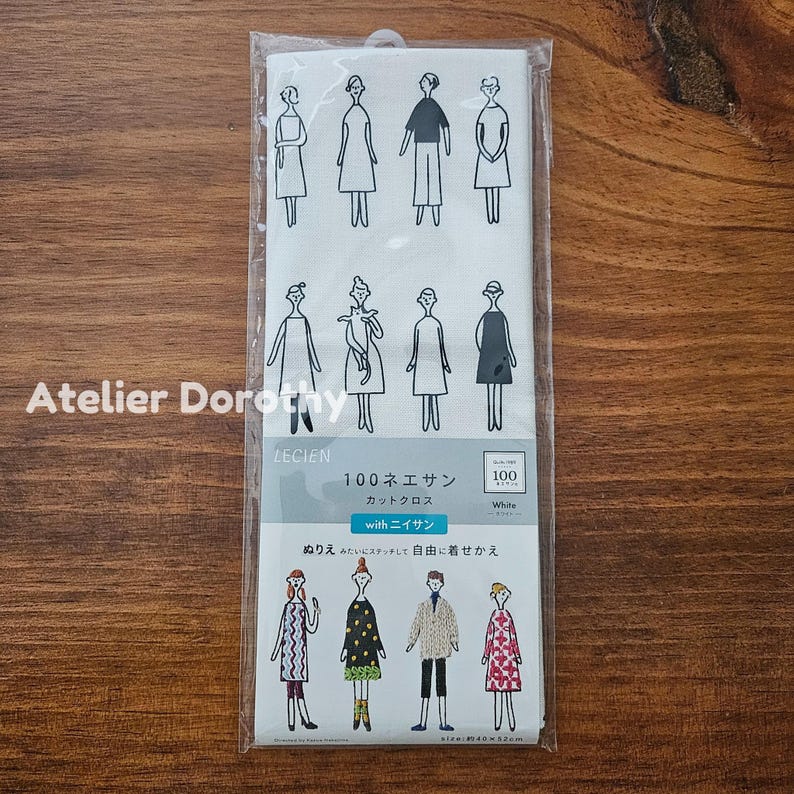 May include: A white fabric panel featuring line drawings of figures in various outfits. The panel includes Japanese text and the words "Atelier Dorothy" in the corner. The fabric is packaged in a clear plastic bag.
