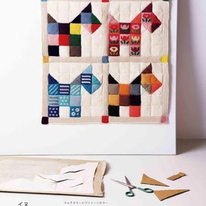 Puede incluir: Primer plano de un tapiz de pared con cuatro cuadrados, cada uno con un dise&ntilde;o de perro. Los perros est&aacute;n hechos de cuadrados y patrones coloridos, con un fondo color crema. El tama&ntilde;o es de 53 cm x 53 cm.