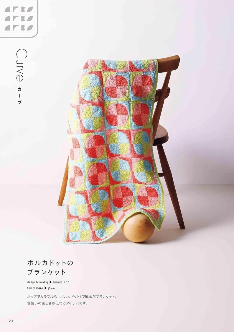Puede incluir: Una colorida manta de ganchillo con un dise&ntilde;o de lunares en cuadrados rojos, rosas, azules y amarillos, colocada sobre una silla de madera. El dise&ntilde;o de la manta se destaca, mostrando la artesan&iacute;a hecha a mano.