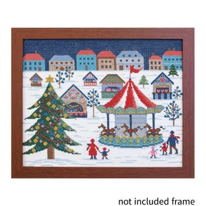 Könnte beinhalten: Kreuzstich-Kunstwerk in einem braunen Holzrahmen, das eine Winterszene darstellt. Die Szene zeigt ein Karussell, Häuser, einen Weihnachtsbaum und Figuren von Menschen. Die Farbpalette umfasst Blau-, Rot-, Grün- und Weißtöne.