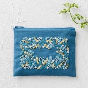 Könnte beinhalten: Türkisfarbene Reißverschlusstasche mit einem gestickten Blumendesign. Die Stickerei zeigt einen rechteckigen Kranz aus gelben, weißen und türkisfarbenen Blumen und Blättern. Die Tasche ist rechteckig und aus einem strukturierten Stoff.
