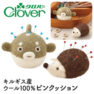 May include: A felt pufferfish pincushion with blue pins and a hedgehog pincushion with red pins. The pincushions are made of brown and white felt. The Clover logo is in the upper left corner.