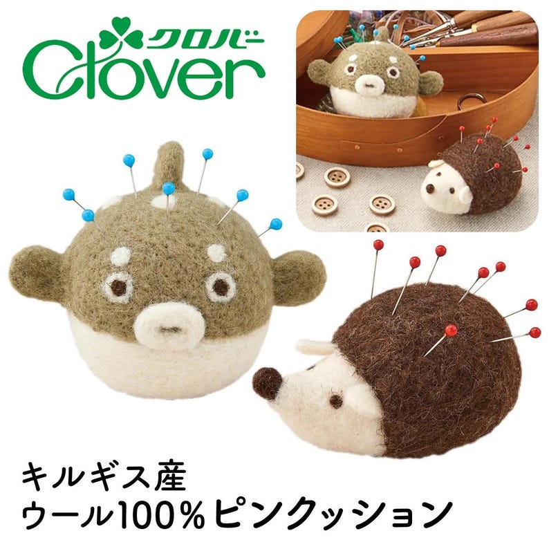 May include: A felt pufferfish pincushion with blue pins and a hedgehog pincushion with red pins. The pincushions are made of brown and white felt. The Clover logo is in the upper left corner.