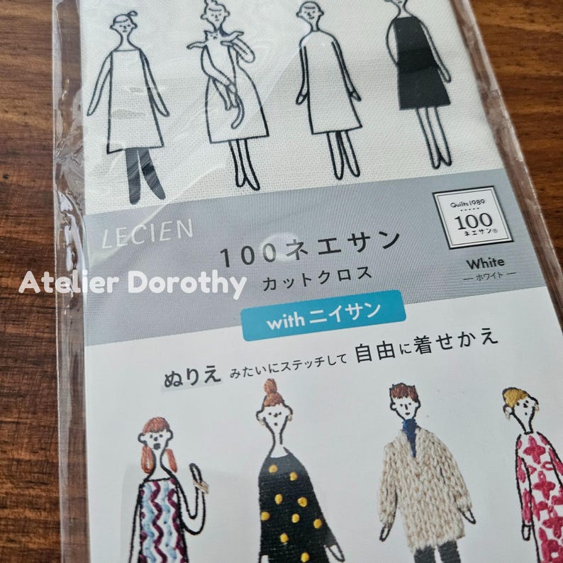 May include: A package of white fabric with a printed design of stylized figures in various outfits. The package includes text in Japanese and English, including "LECIEN" and "Atelier Dorothy." The fabric is designed for stitching.