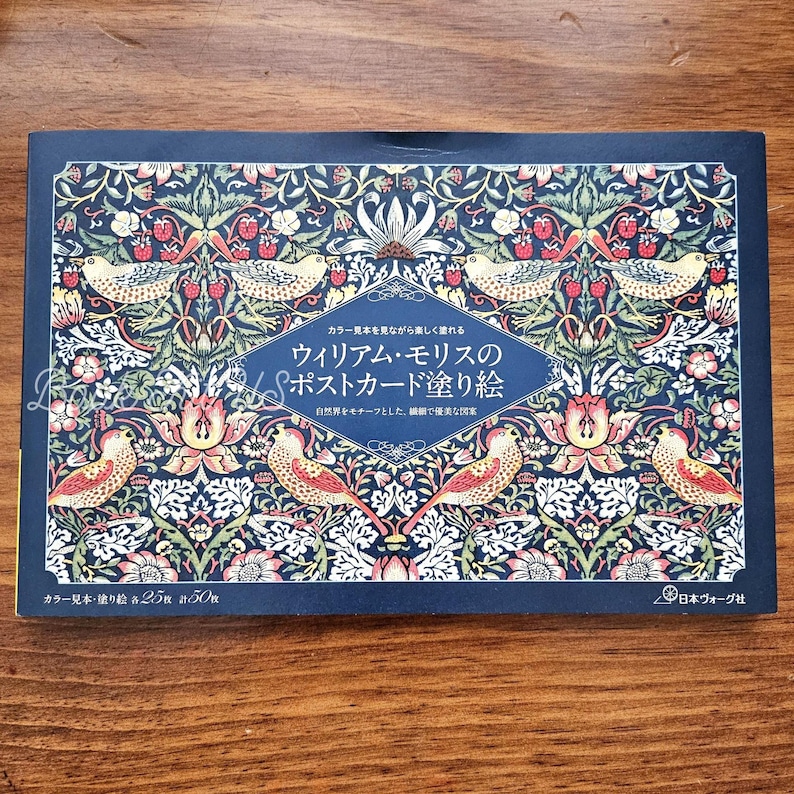 May include: A navy blue postcard set featuring a detailed floral and bird design in red, yellow, and green. The set includes text in Japanese and is a coloring book with 25 postcards.