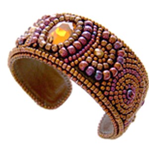 Puede incluir: Un brazalete de puño de cuentas con una gran piedra preciosa de color ámbar en el centro. El brazalete está hecho con cuentas pequeñas, marrones, moradas y doradas en un patrón de remolino.