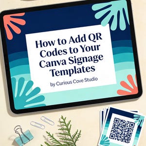 May include: A tablet displays the text "How to Add QR Codes to Your Canva Signage Templates" by Curious Cove Studio. The design includes blue, teal, and coral accents. A stylus, paper clips, a binder clip, and a sprig of greenery are also present.